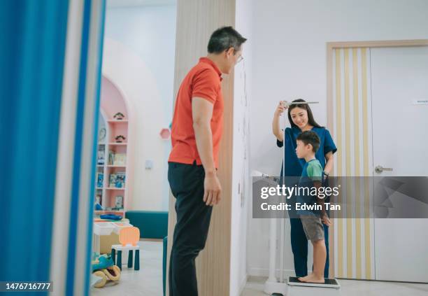 asian chinese female paediatric nurse measuring small boy height and weight in clinic father watching - human age stock pictures, royalty-free photos & images