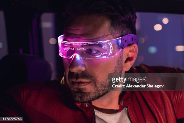 male portrait of one man indoors the car. neon light concept photography, futuristic photo with red color lighting indoors the vehicle. person wear glowing eyeglasses and driving vehicle - red light portrait stock pictures, royalty-free photos & images
