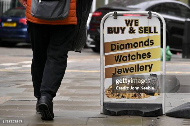 Sign advertising "We buy diamonds, watches and jewellery is displayed outside a jewellers in Hatton Garden on March 23, 2023 in London, England. The...