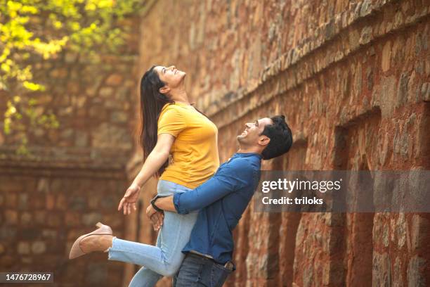 happy man lifting up his girlfriend in the air - india couple lift stock pictures, royalty-free photos & images