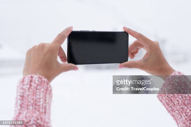 hand holding smartphone and takes pictures of beautiful winter landscape in snow-covered forest. hand holding smartphone device on snow winter background. - smart phone camera stock pictures, royalty-free photos & images