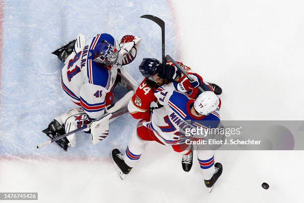 Goaltender Jaroslav Halak and Niko Mikkola of the New York Rangers tangle with Ryan Lomberg of the Florida Panthers at the FLA Live Arena on March...