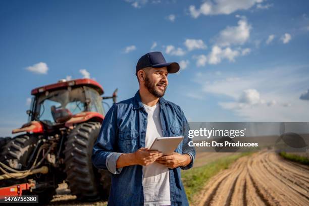 porträt eines bauern mit tablet vor seinem traktor - landwirtschaftliche maschine stock-fotos und bilder