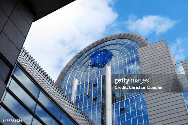 european flag in front of european parliament building. - european parliament stock-fotos und bilder