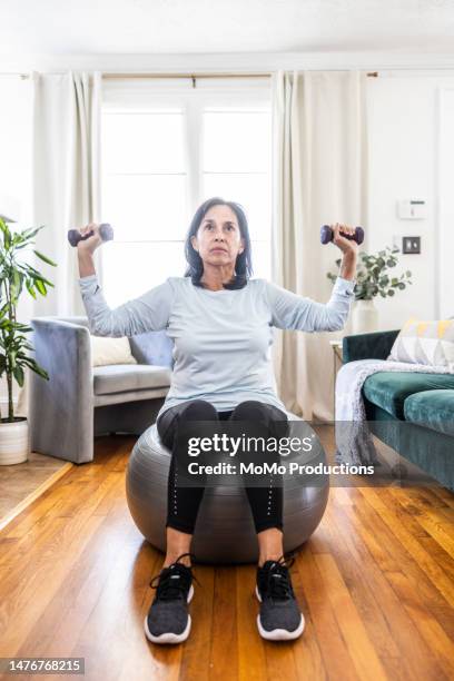 senior woman lifting small dumbbells at home - レギンス　 ストックフォトと画像
