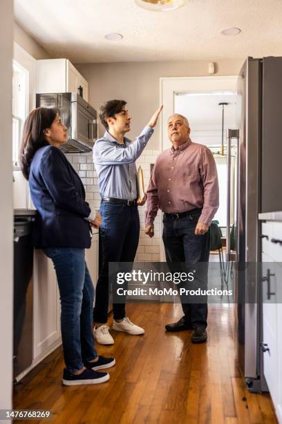 senior couple looking at home with real estate agent in kitchen - landlord stock pictures, royalty-free photos & images
