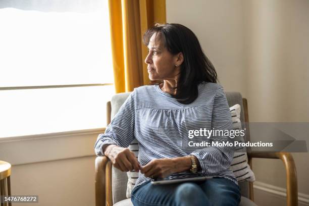 senior woman looking out window at home - introspection stock pictures, royalty-free photos & images