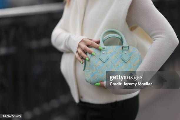 Sonia Lyson wearing Studio AR pants, white turtleneck sweater and beige vest, Louis Vuitton tie dye baby blue yellow logo leather bag on March 22,...