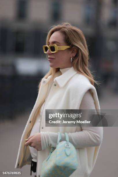 Sonia Lyson wearing Studio AR pants, white turtleneck sweater and beige vest, Louis Vuitton tie dye baby blue yellow logo leather bag and Loewe...