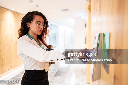 Young woman pressing elevator button in the entrance hall at office