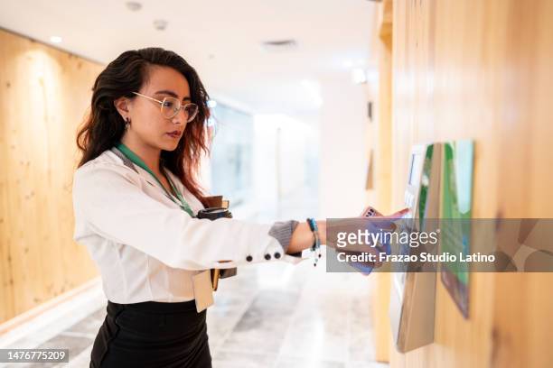 young woman pressing elevator button in the entrance hall at office - employee badge stock pictures, royalty-free photos & images