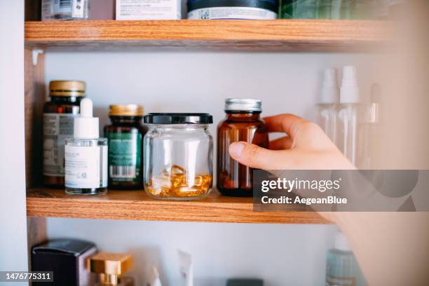 femme prenant des vitamines de l’armoire de salle de bain - armoire de toilette photos et images de collection