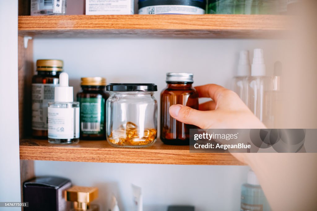 浴室のキャビネットからビタミンを摂取する女性