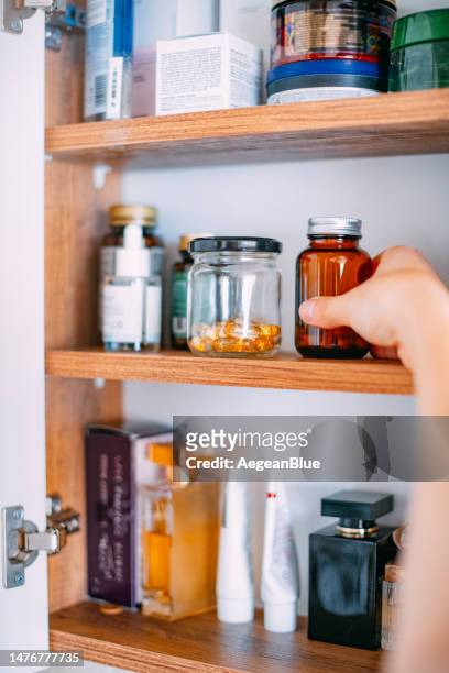woman taking vitamins from bathroom cabinet - medicine cabinet 個照片及圖片檔