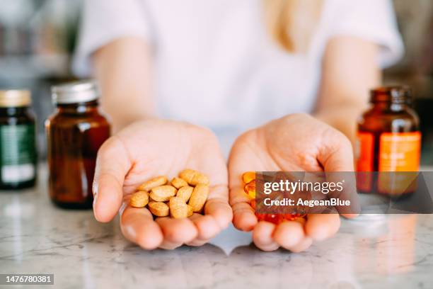 mujer sosteniendo píldoras de vitaminas en sus palmas - condición natural fotografías e imágenes de stock
