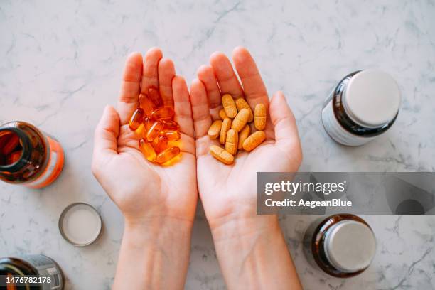 donna che tiene le pillole vitaminiche nei suoi palmi - vitamina c foto e immagini stock