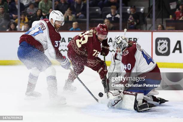 Travis Boyd of the Arizona Coyotes attempts a shot on goaltender Alexandar Georgiev and J.T. Compher of the Colorado Avalanche during the first...