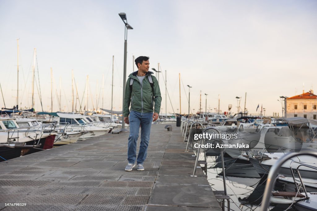 Male Solo Traveler Walking And Exploring A Marina