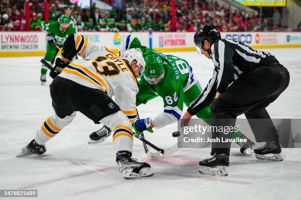 Jesperi Kotkaniemi of the Carolina Hurricanes faces off with Charlie Coyle of the Boston Bruins during the first period at PNC Arena on March 26,...