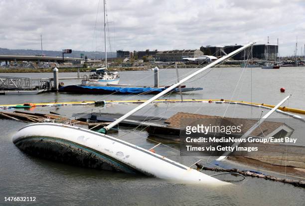Containment boom surrounds a partially sunk sailboat and houseboat at the Jack London Aquatic Center in Oakland, Calif., on Thursday, March 23, 2023....
