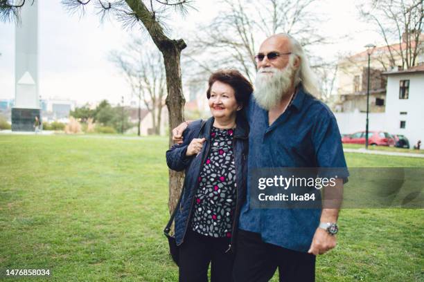 coppia eterosessuale senior che cammina all'aperto nel parco - tre quarti anteriore foto e immagini stock