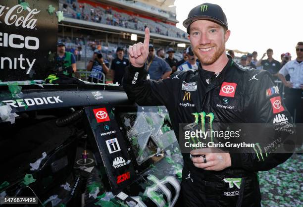 Tyler Reddick, driver of the Monster Energy Toyota, poses after placing the winner sticker on his car in victory lane after winning the NASCAR Cup...
