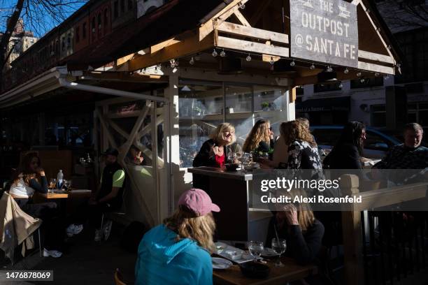 People sit at a restaurant's outdoor dining space as temperatures reach above 60 degrees during the first weekend of spring on March 26, 2023 in New...