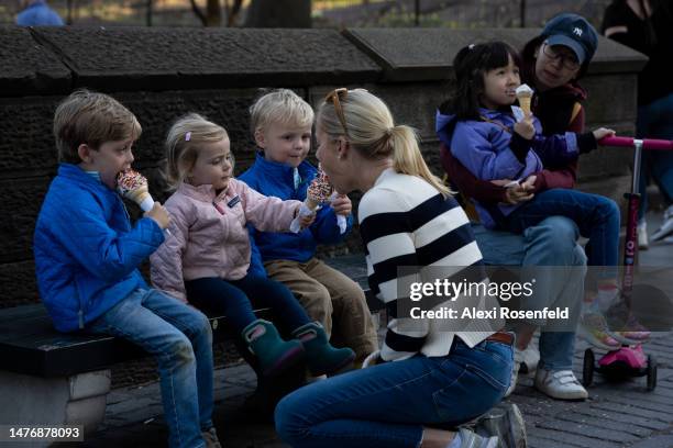 Woman eats ice cream from a girl near in Central Park as temperatures reach above 60 degrees during the first weekend of spring on March 26, 2023 in...
