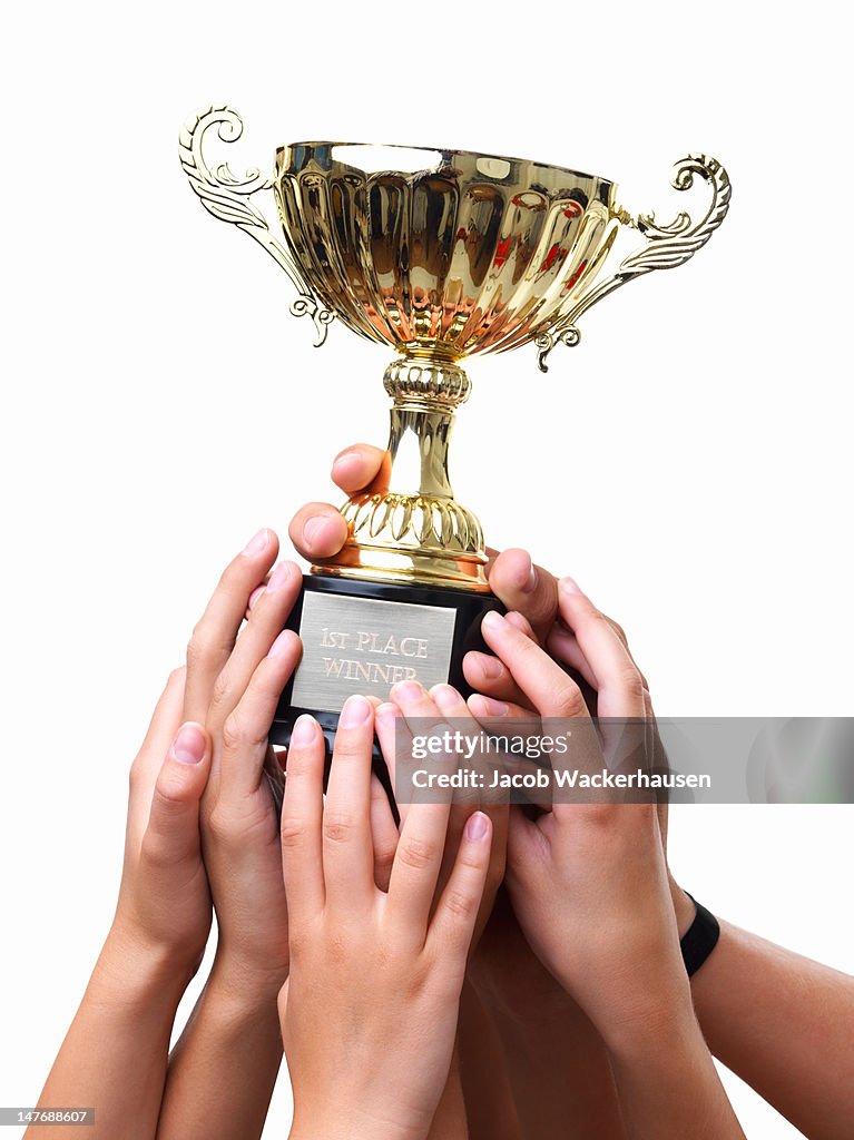 Close-up of hands holding winning cup against white background