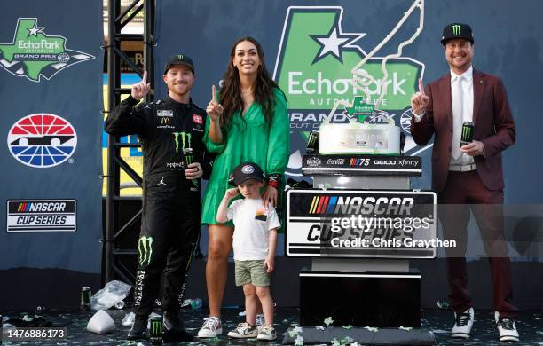 Tyler Reddick, driver of the Monster Energy Toyota, his wife Alexa, son Beau and retired NASCAR driver and advisor to 23XI Racing, Kurt Busch pose...