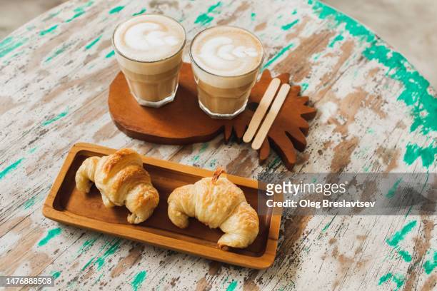 top view of two croissants and cappuccino on shabby wooden table surface - breakfast to go stock-fotos und bilder