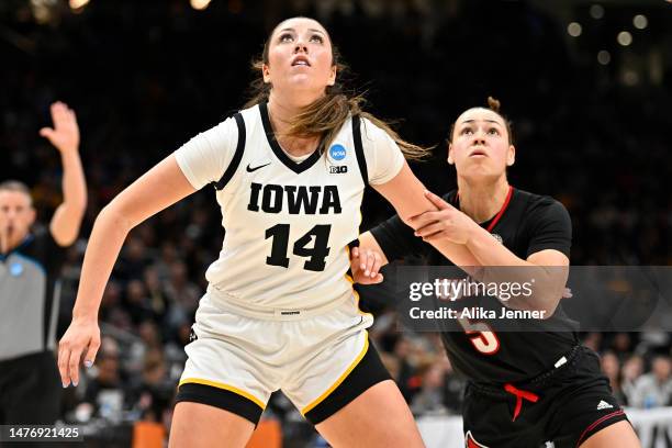 McKenna Warnock of the Iowa Hawkeyes and Mykasa Robinson of the Louisville Cardinals compete for a rebound during the third quarter in the Elite...