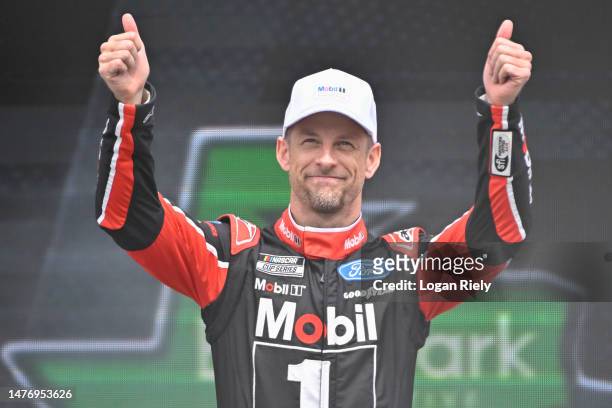 Jenson Button, driver of the Mobil 1 Ford, gives a thumbs up to fans as he walks onstage during driver intros prior to the NASCAR Cup Series EchoPark...
