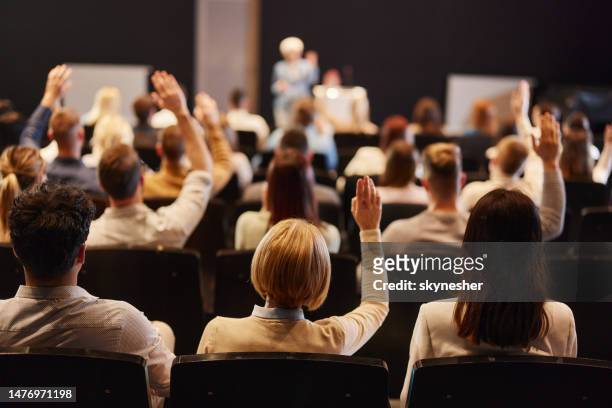 back view of crowd of people raising hands on a seminar in convention center. - deelnemer stockfoto's en -beelden