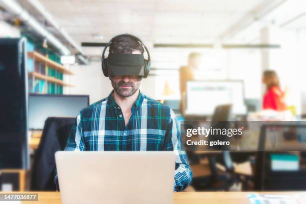 man working at laptop in office with headphones and anti distraction cap - wearing-blinders stock pictures, royalty-free photos & images