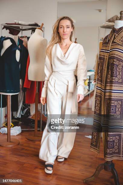 beautiful woman strolling down the salon in her new tailor made outfit - jumpsuit fashion stock pictures, royalty-free photos & images