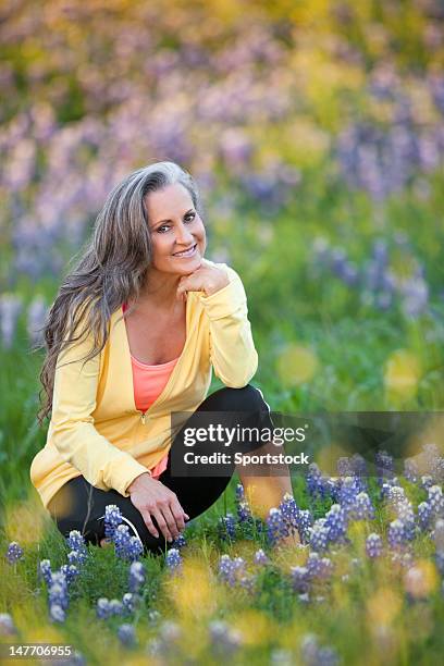 middle aged female sitting in texas bluebonnets - one woman only kneeling stock pictures, royalty-free photos & images