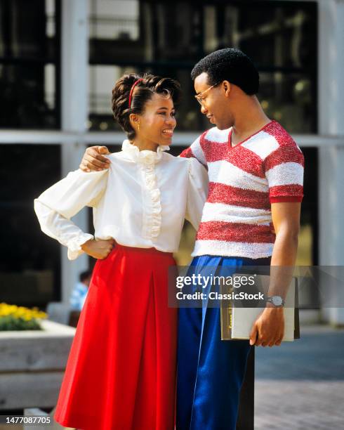 1980s romantic couple on campus smiling arms embracing looking at one another man carrying notebooks bppks.
