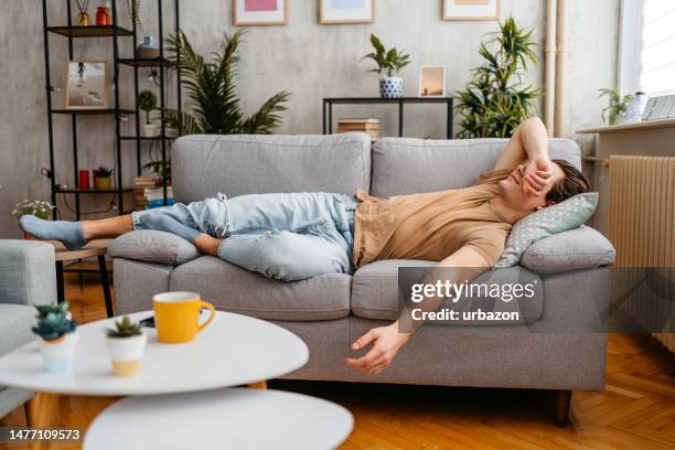 giovane che dorme sul divano a casa - supino foto e immagini stock