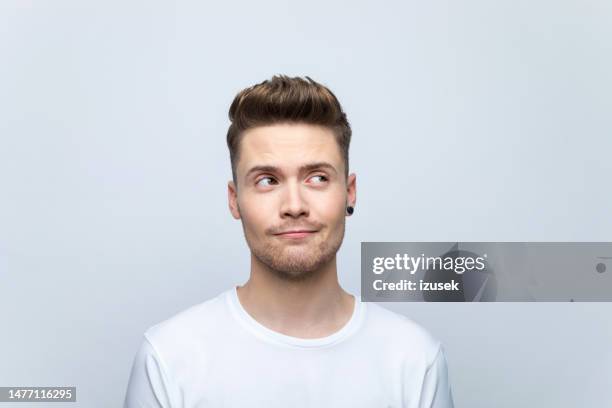 jeune homme plein qui lève les yeux - sourire narquois photos et images de collection