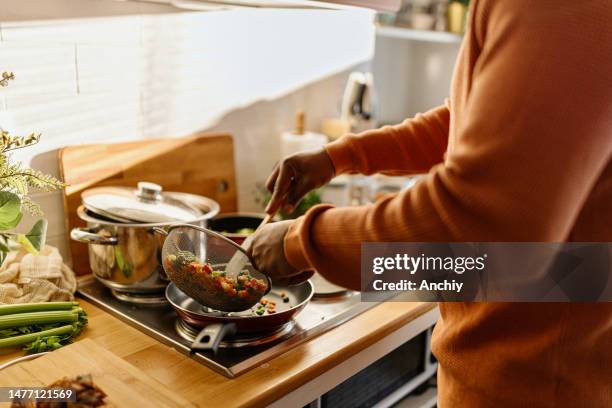 man preparing quinoa vegetable mix cooked in a frying pan - meal stock pictures, royalty-free photos & images