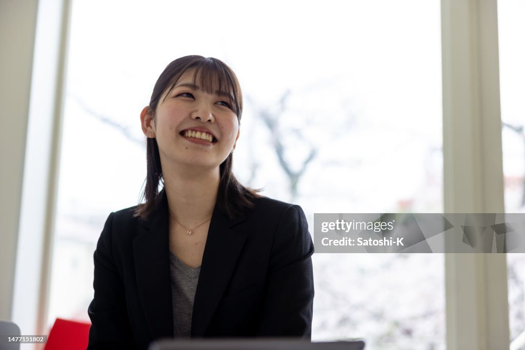 Young business woman looking at screen on wall and discussing with colleagues joining from home office