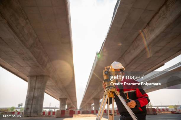 a civil engineer is working using surveyor equipment at road construction site. personnel concept for construction work. surveyor equipment. - civil engineer - fotografias e filmes do acervo