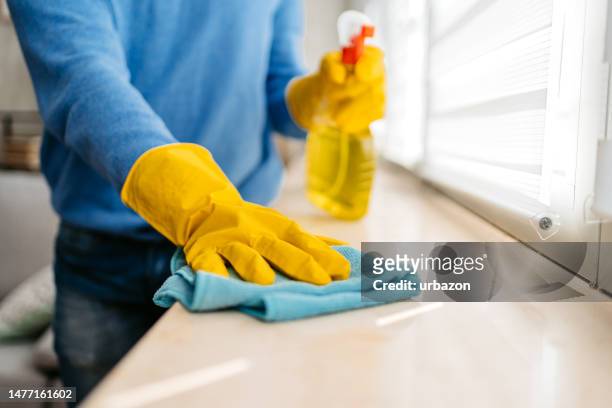 young man cleaning his window sill at home - ledge stock pictures, royalty-free photos & images