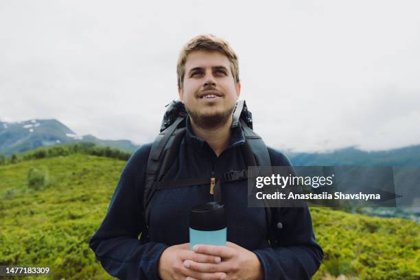 ein mann mit rucksack und thermobecher wandert in den sommerbergen norwegens - thermo becher stock-fotos und bilder