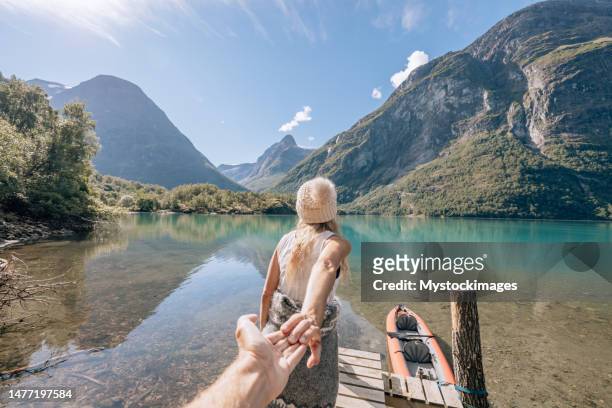pov di coppia sul molo di legno, la ragazza conduce il fidanzato e la segue - fjord foto e immagini stock
