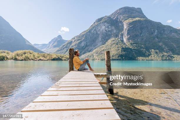 peaceful man relaxing on wooden pier above beautiful lake, he arrived with a canoe - rowboat bildbanksfoton och bilder