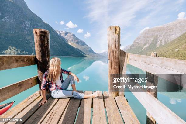 peaceful woman relaxing on wooden pier above beautiful lake, she arrived with her canoe - rowboat bildbanksfoton och bilder