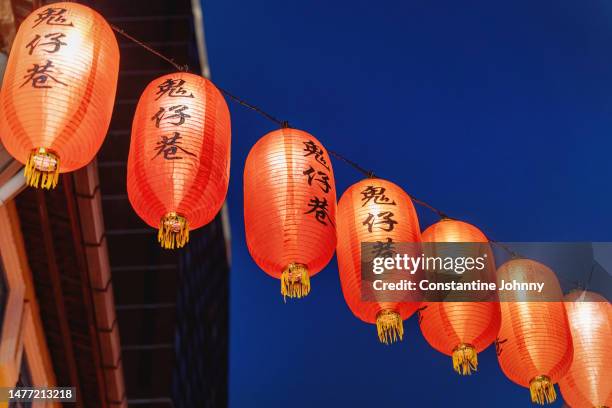 string of chinese lanterns with writing on them hanging from a building. - chinese script stock pictures, royalty-free photos & images