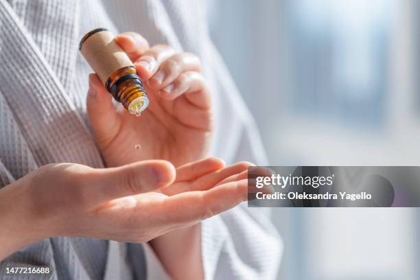 woman dripping essential oil on hand - aromaterapia foto e immagini stock